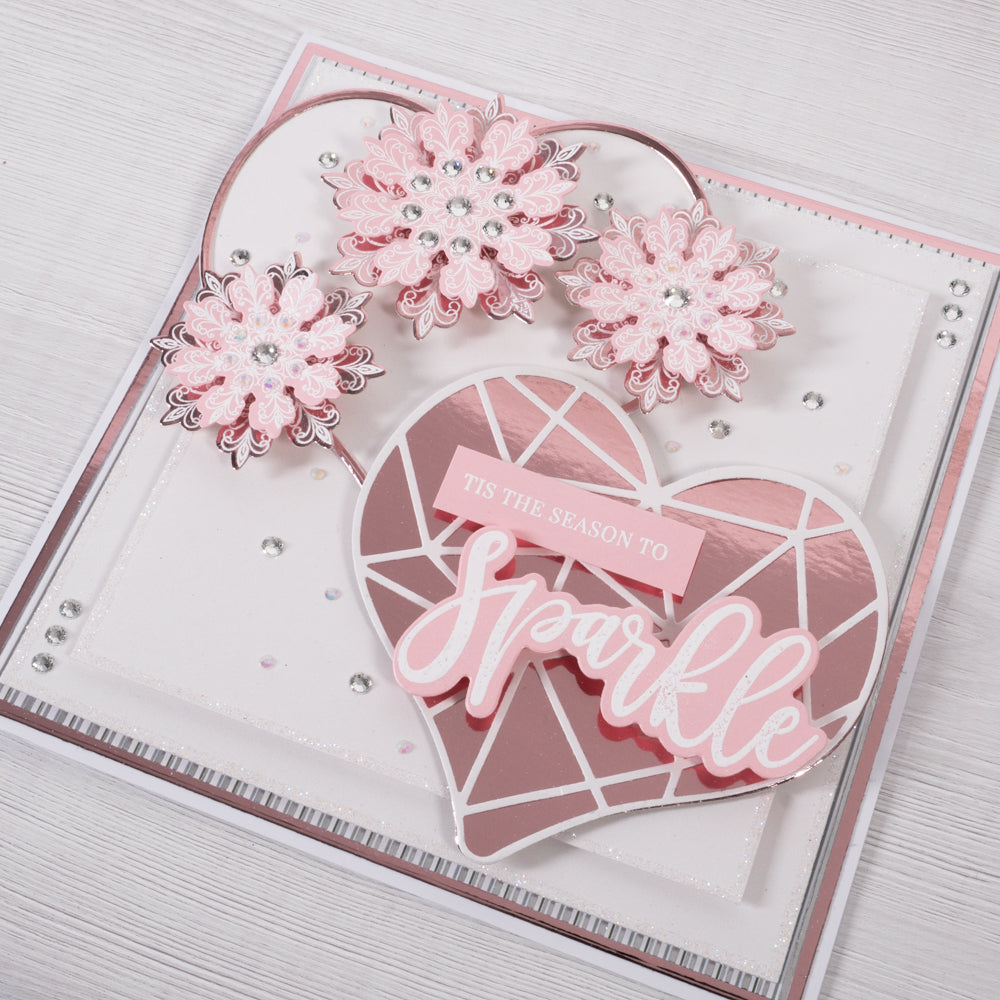 Learn how to create this pretty pink and rose gold heart Christmas Card featuring heart shaped layers and 3D paper flowers from Chloes Creative Cards.