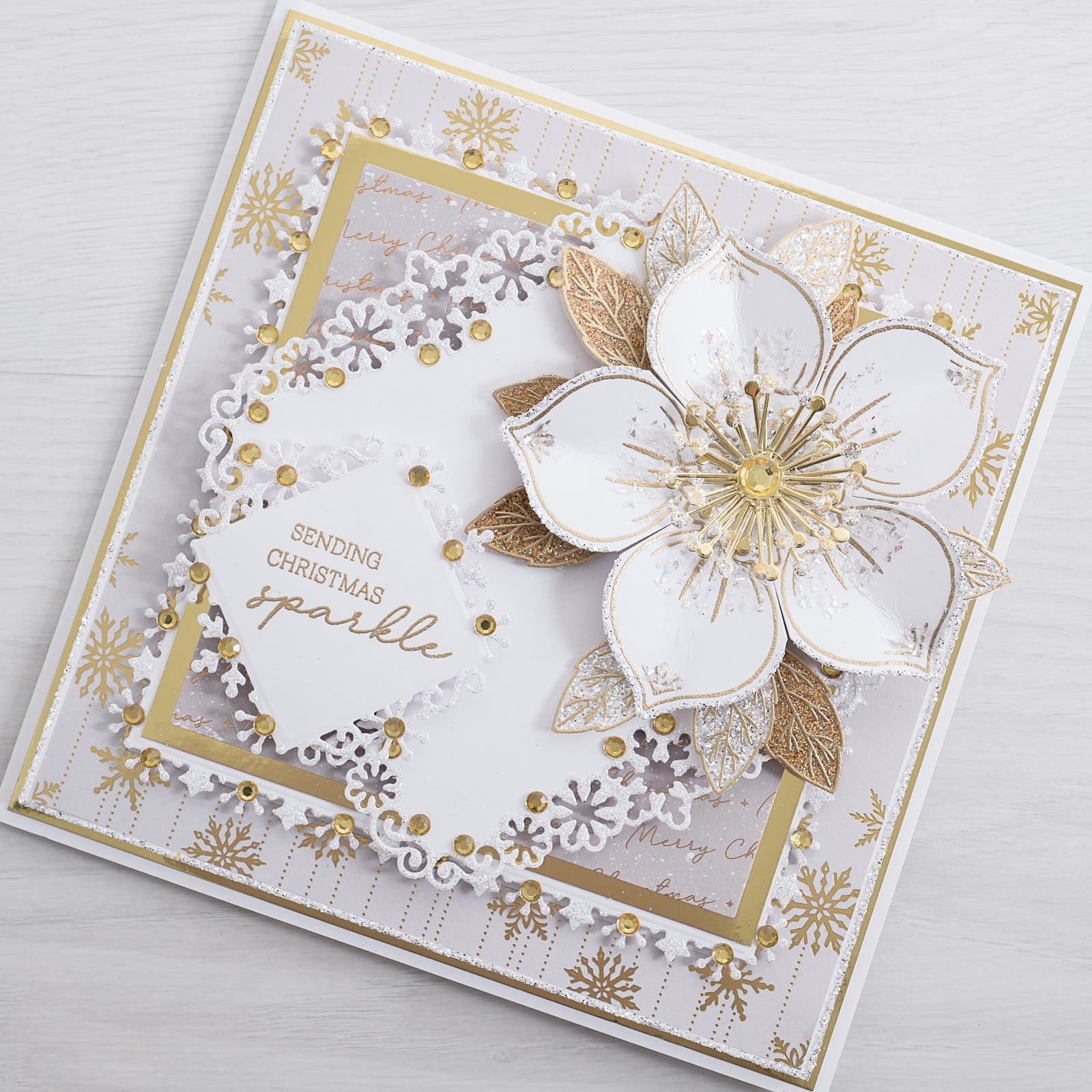 Learn how to make your own beautiful Christmas cards at home using this step-by-step tutorial fro Chloes Creative Cards. This classic white and gold Christmas flower card is a timeless classic filled with sparkling glitter!