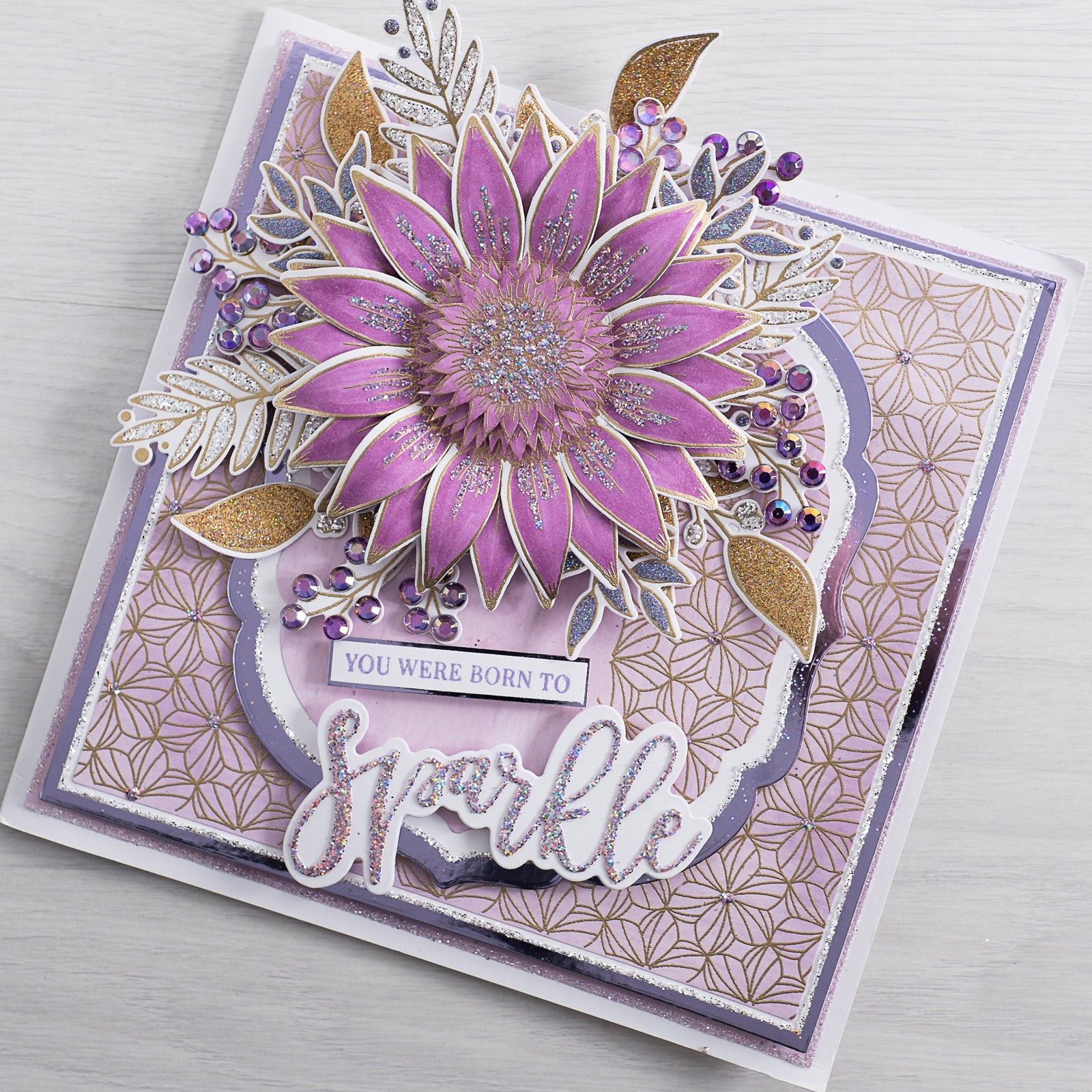 Learn how to create this bright pink and purple 3D flower card filled with glitter and sparkle using our free step-by-step card-making tutorial from Chloes Creative Cards.